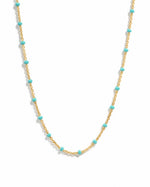 Delicate gold turquoise beaded enamel necklace on a white background.