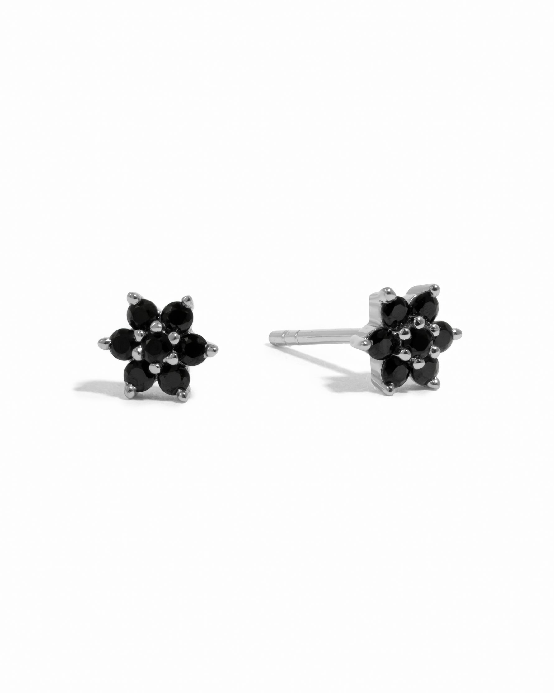 Sterling silver delicate black onyx gemstone flower stud earrings on white background.