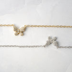 Close-up of tiny cz butterfly pendant necklaces in gold and silver on marble background. 