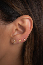 Model wearing gold plain star stud earrings in a celestial stack featuring a diamond lightning bolt, a plain star, and a diamond moon stud.