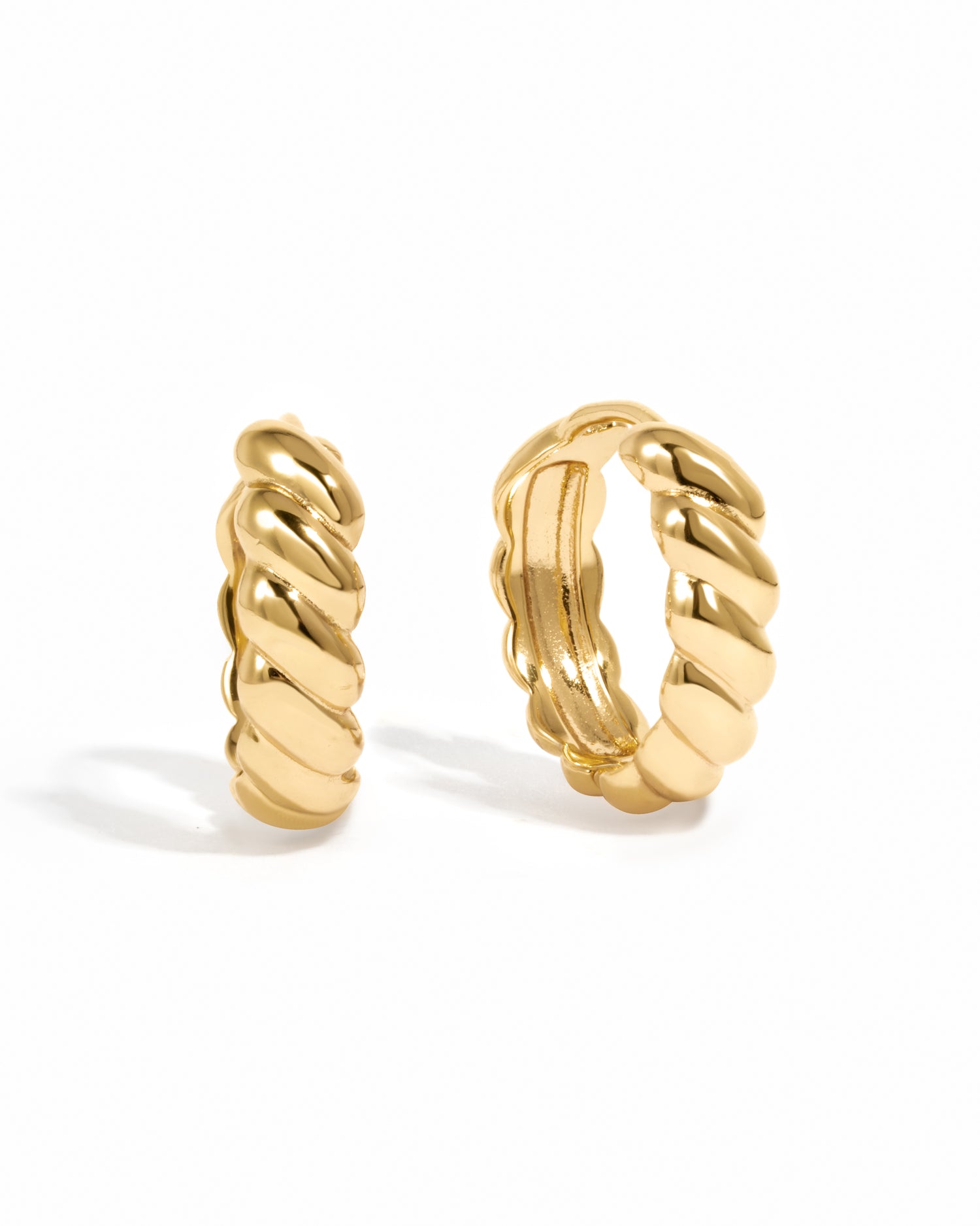 Trendy gold croissant hoop earrings on white background. 