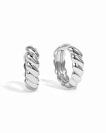 Trendy silver croissant hoop earrings on white background. 
