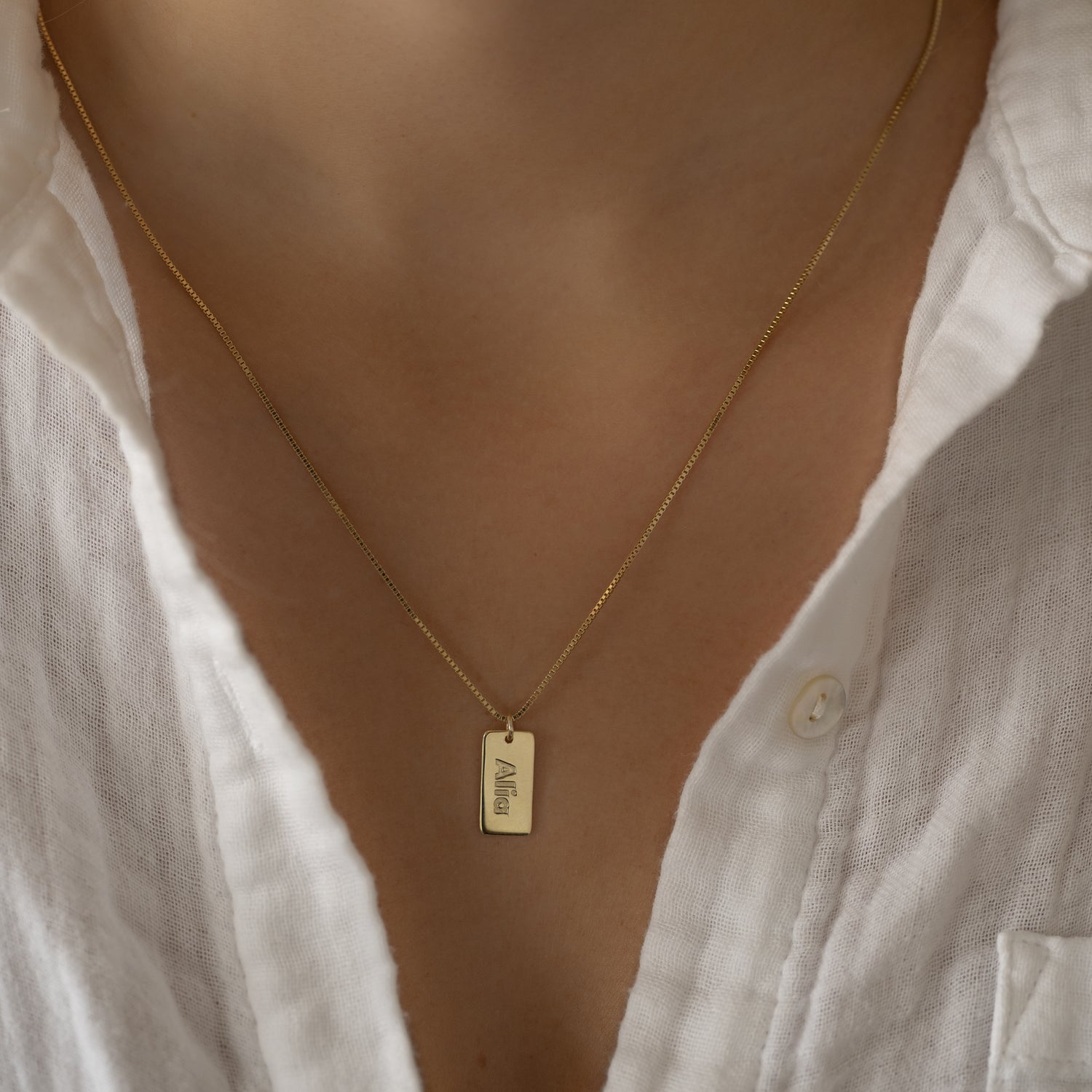 Model wearing dainty gold custom dog tag name necklace