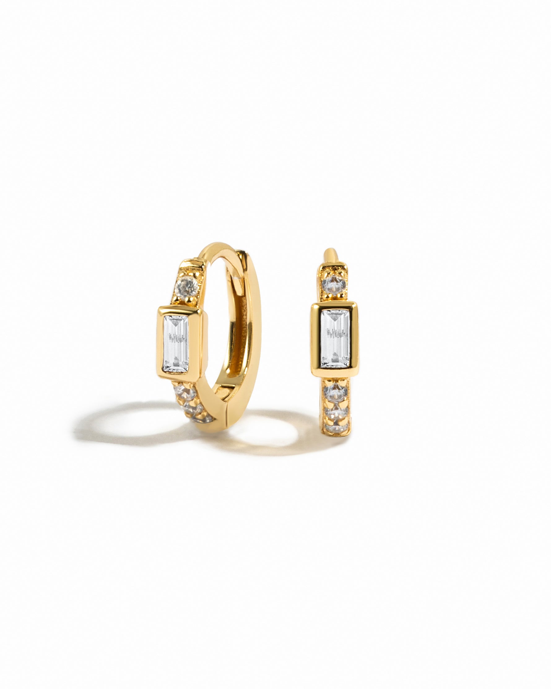 Small gold hoop earrings with cubic zirconia pave stones and a baguette cut stone in the center
