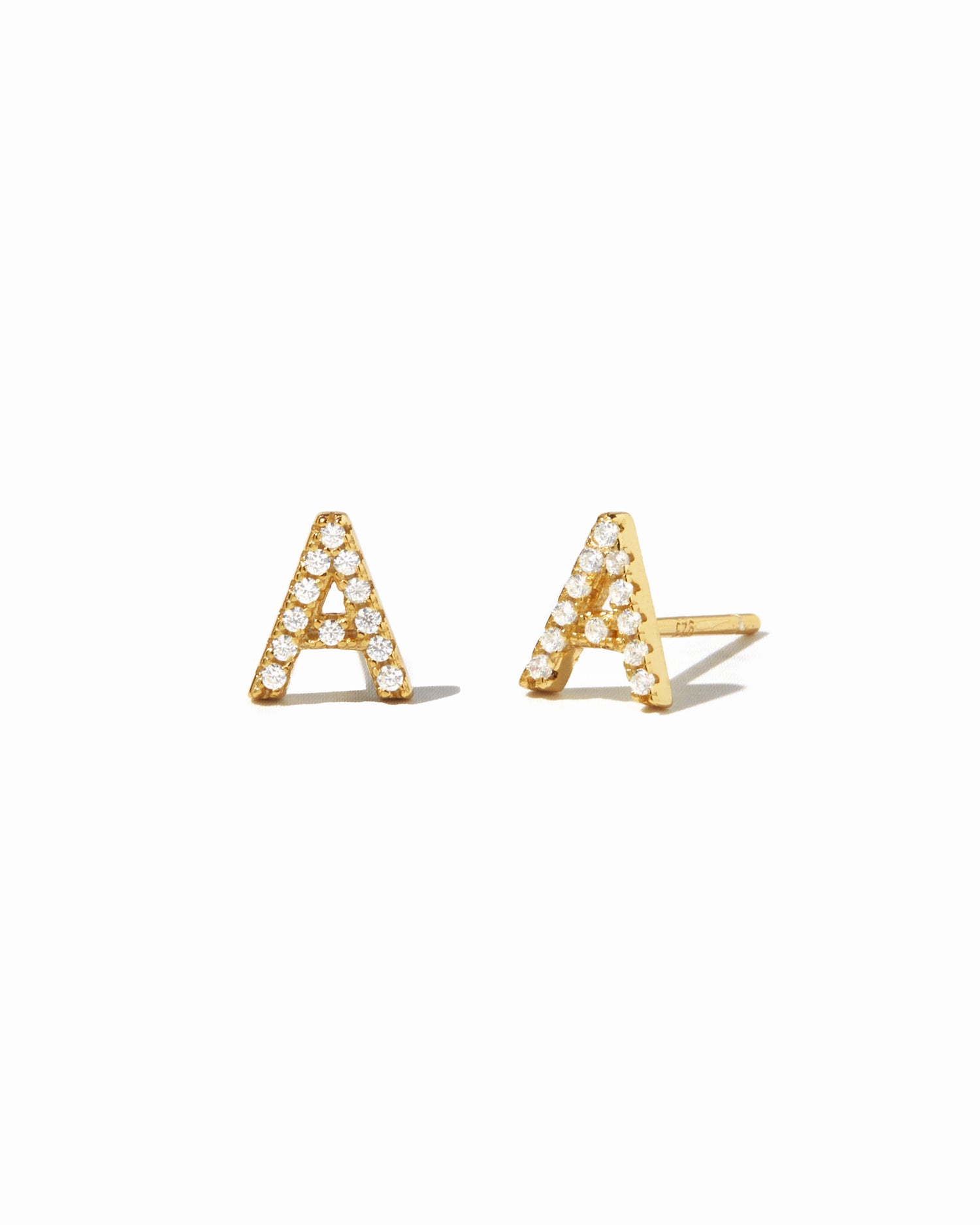 Tiny CZ studded gold initial earrings in the letter "A".