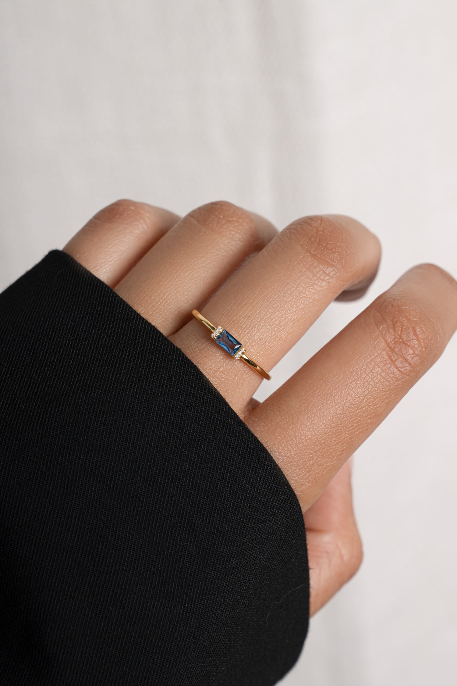 Model wearing dainty gold aquamarine birthstone baguette ring.
