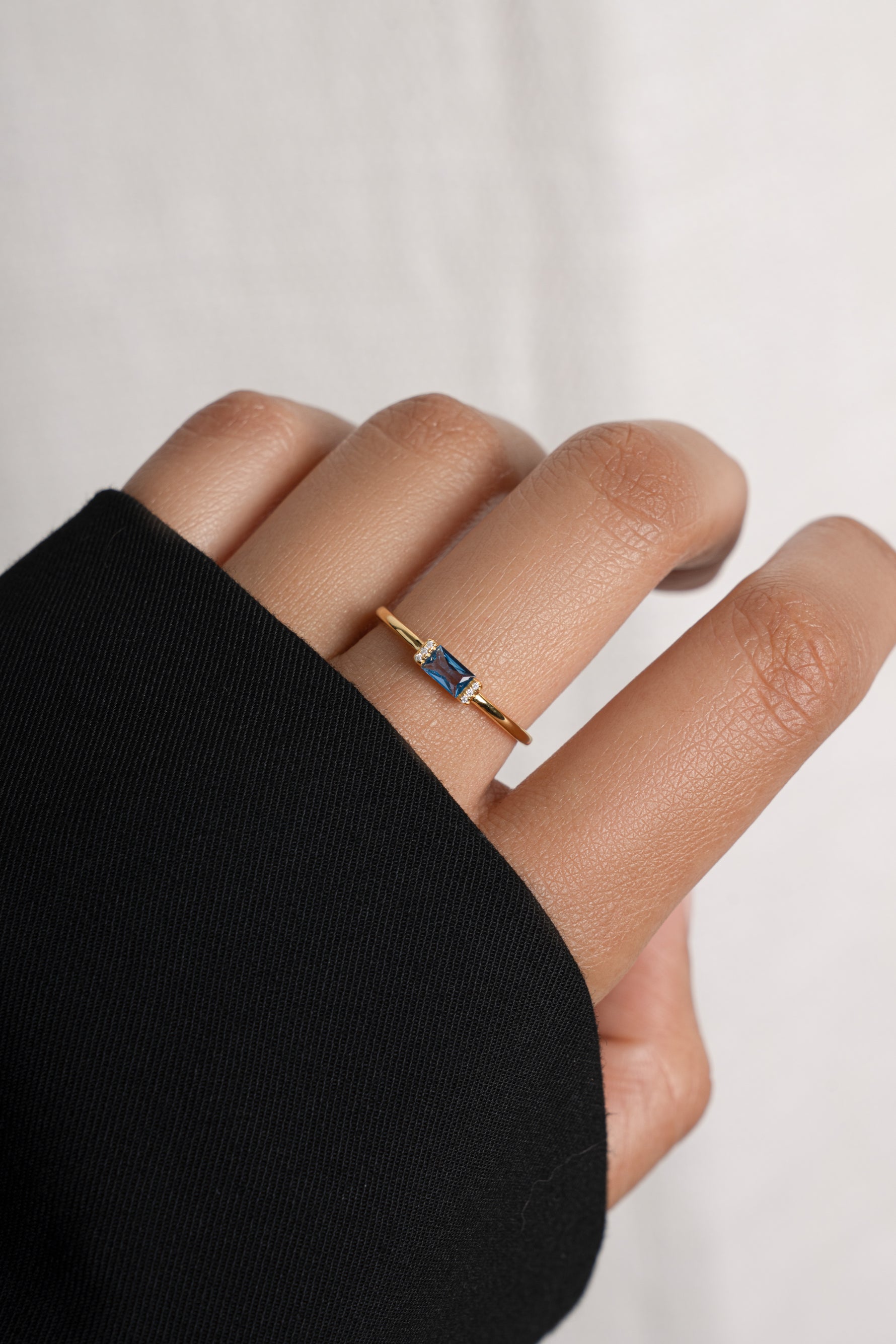 Model wearing dainty gold aquamarine birthstone baguette ring.