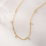 Gold paperclip dainty chain necklace with cz charms on a plain background.