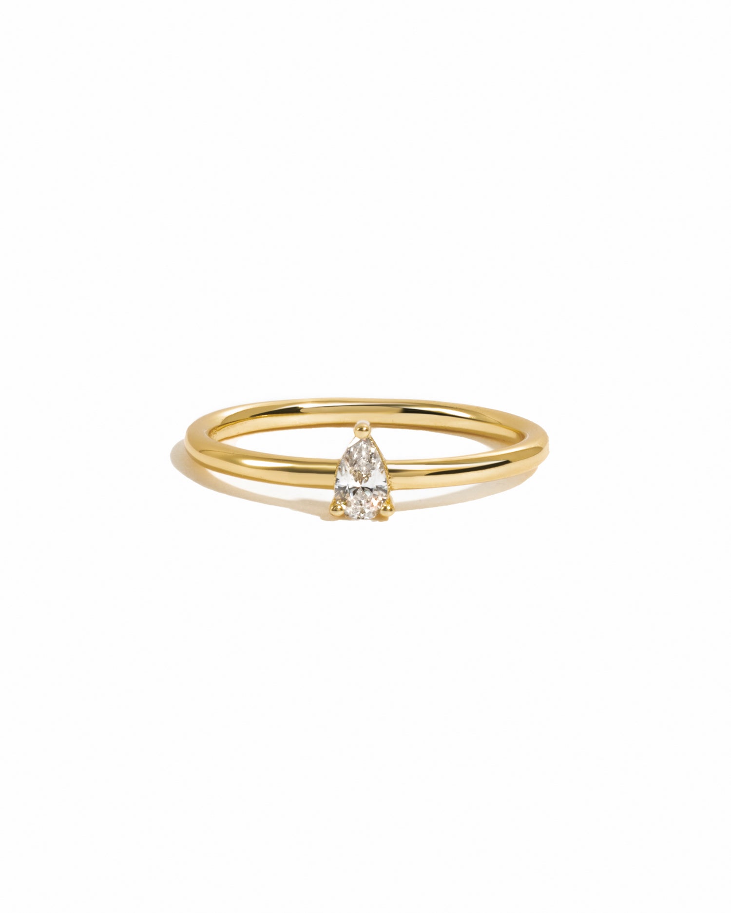 Dainty solitaire pear ring on white background.