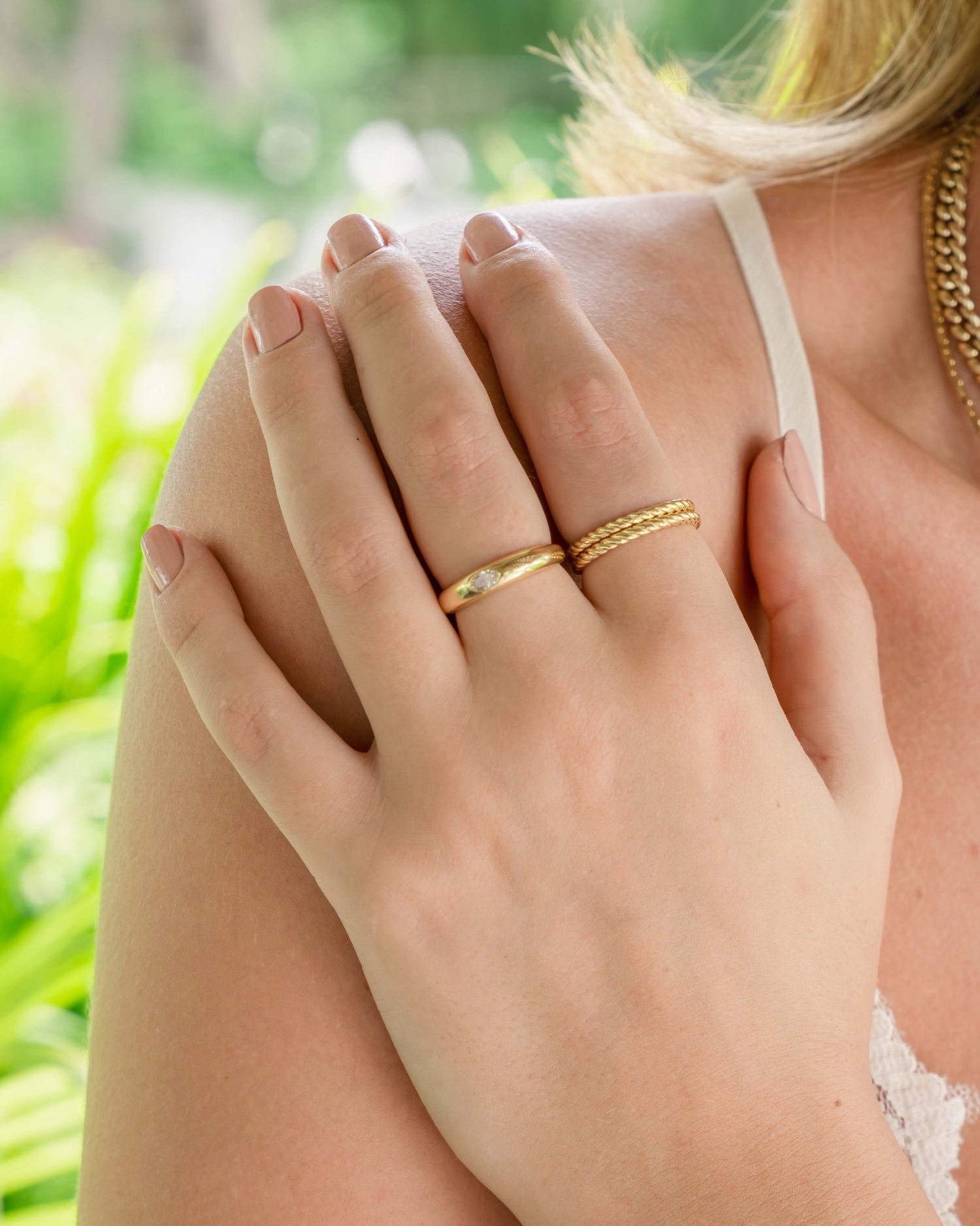 Model wearing gold bezeled dome ring paired with two thick spiral stacking bands in gold. 
