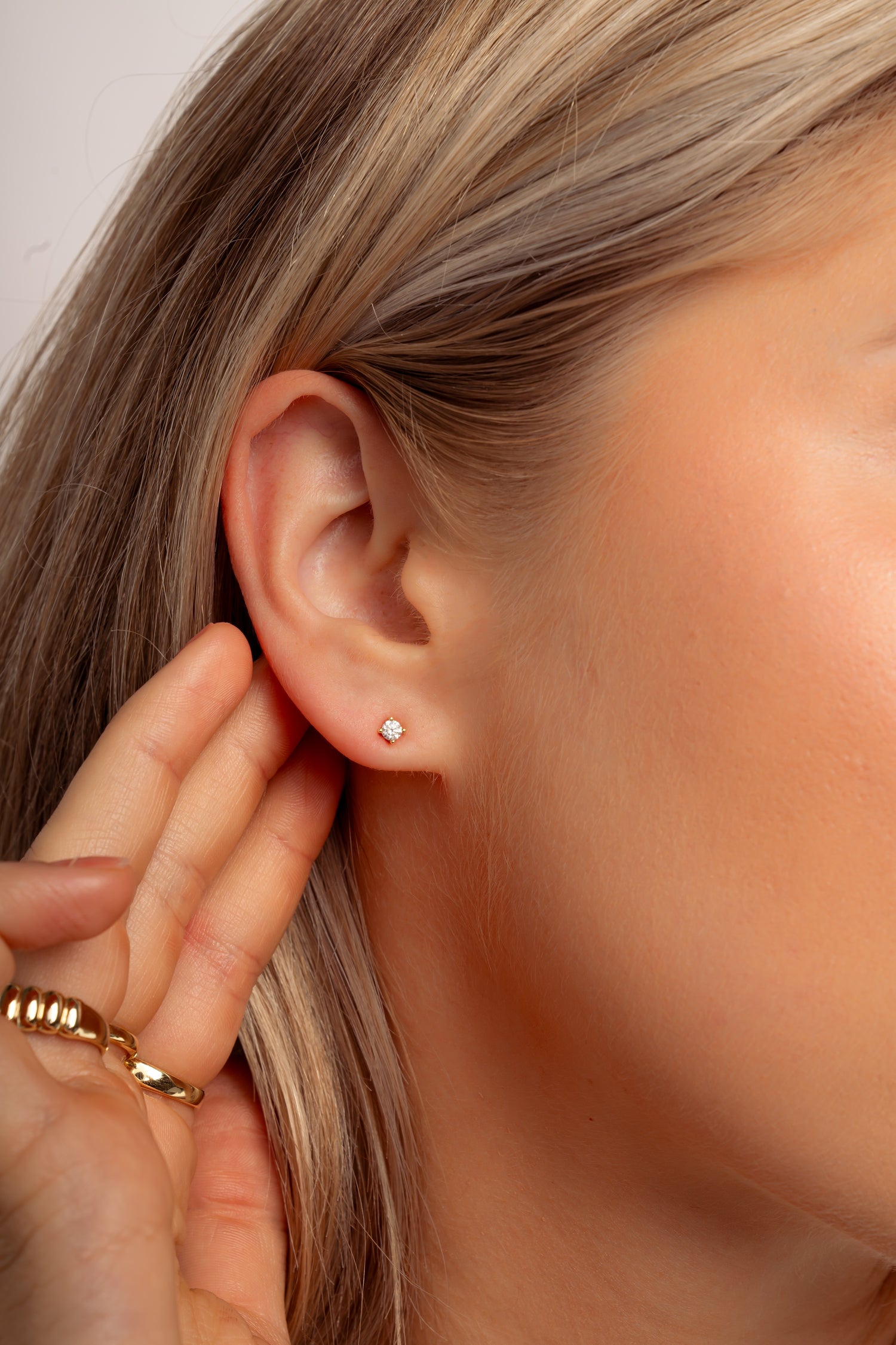 Model wearing classic dainty gold stud earrings. 