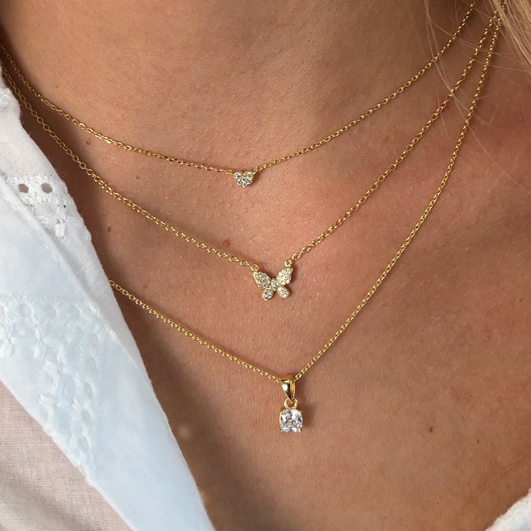 Model wearing three minimalist and timeless gold chain necklaces with cz pendants. 