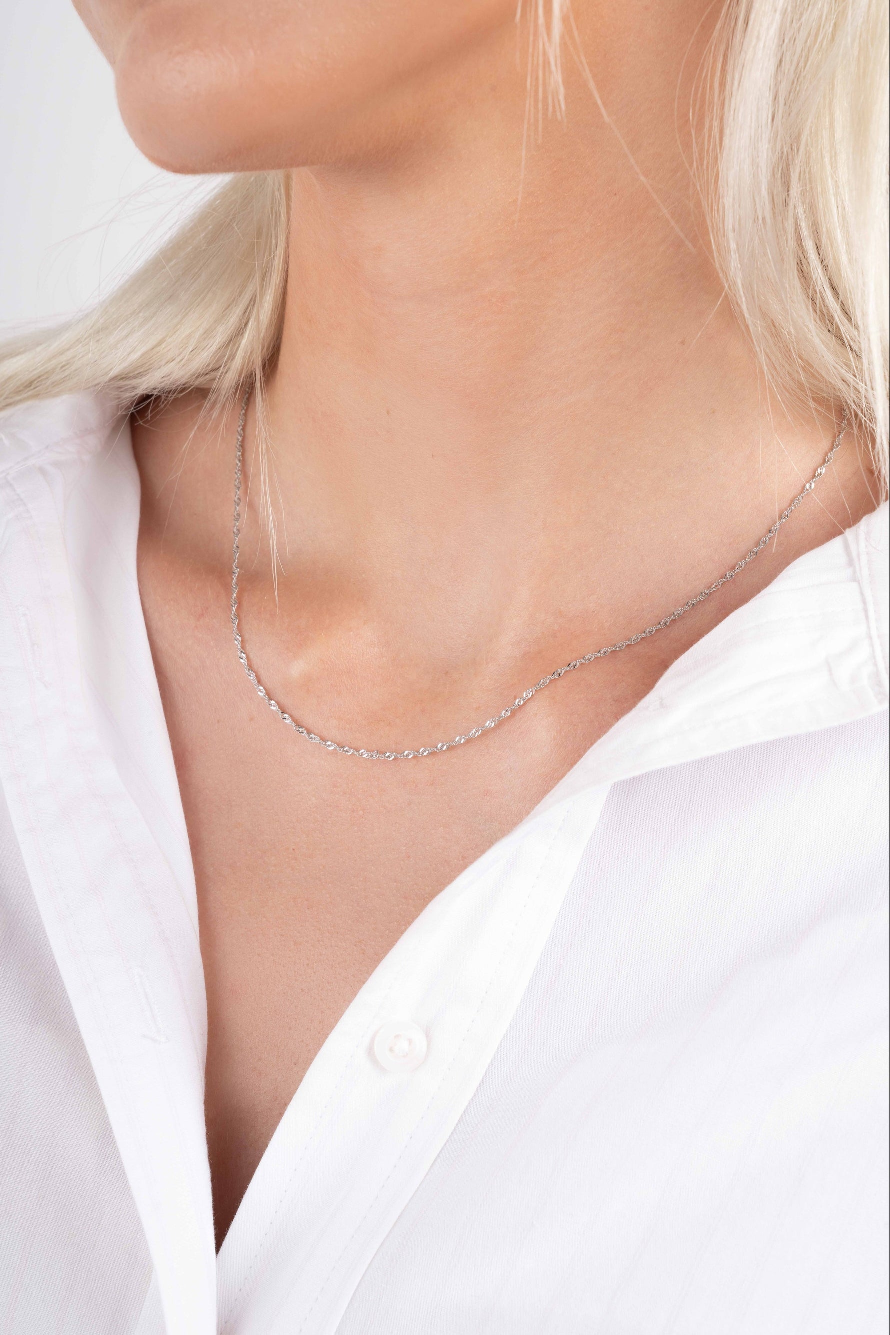 Model wearing minimalist silver twisted chain necklace. 