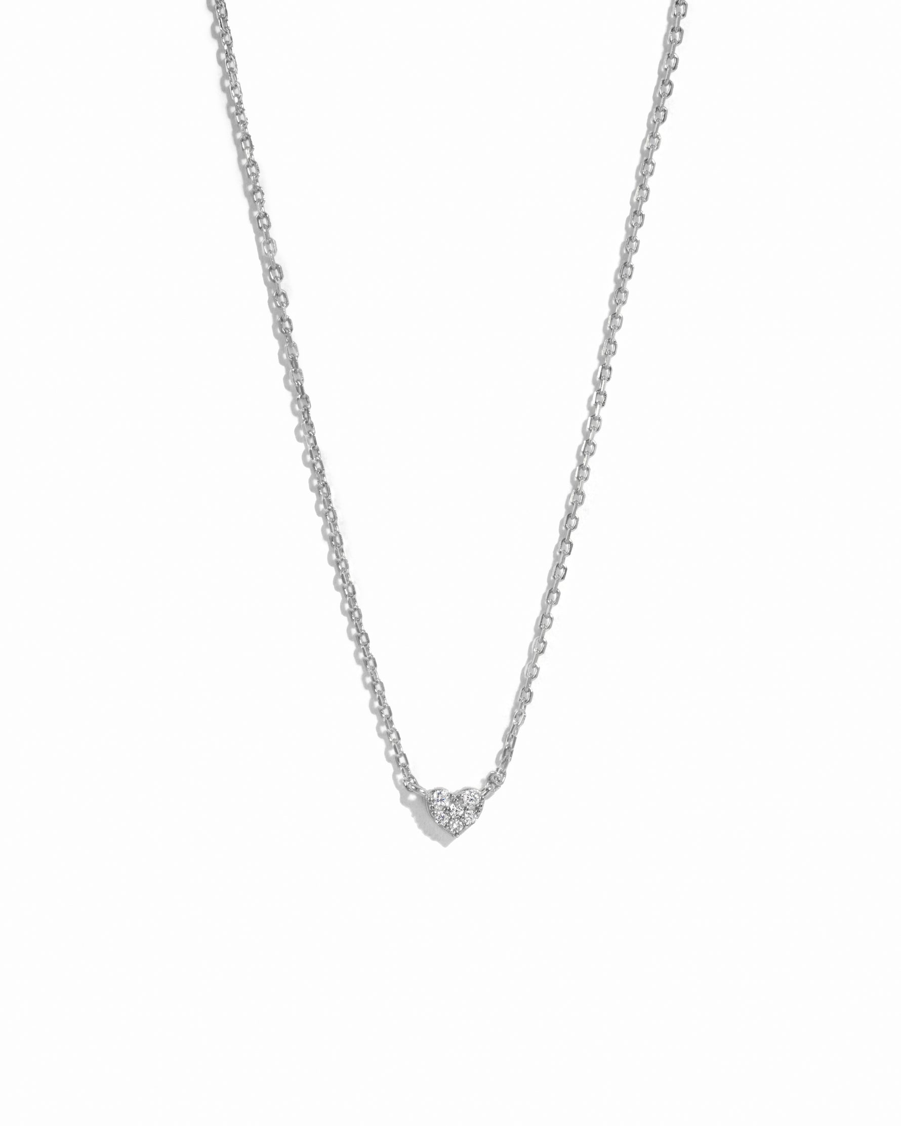 Silver minimalist tiny cz heart necklace on white background. 