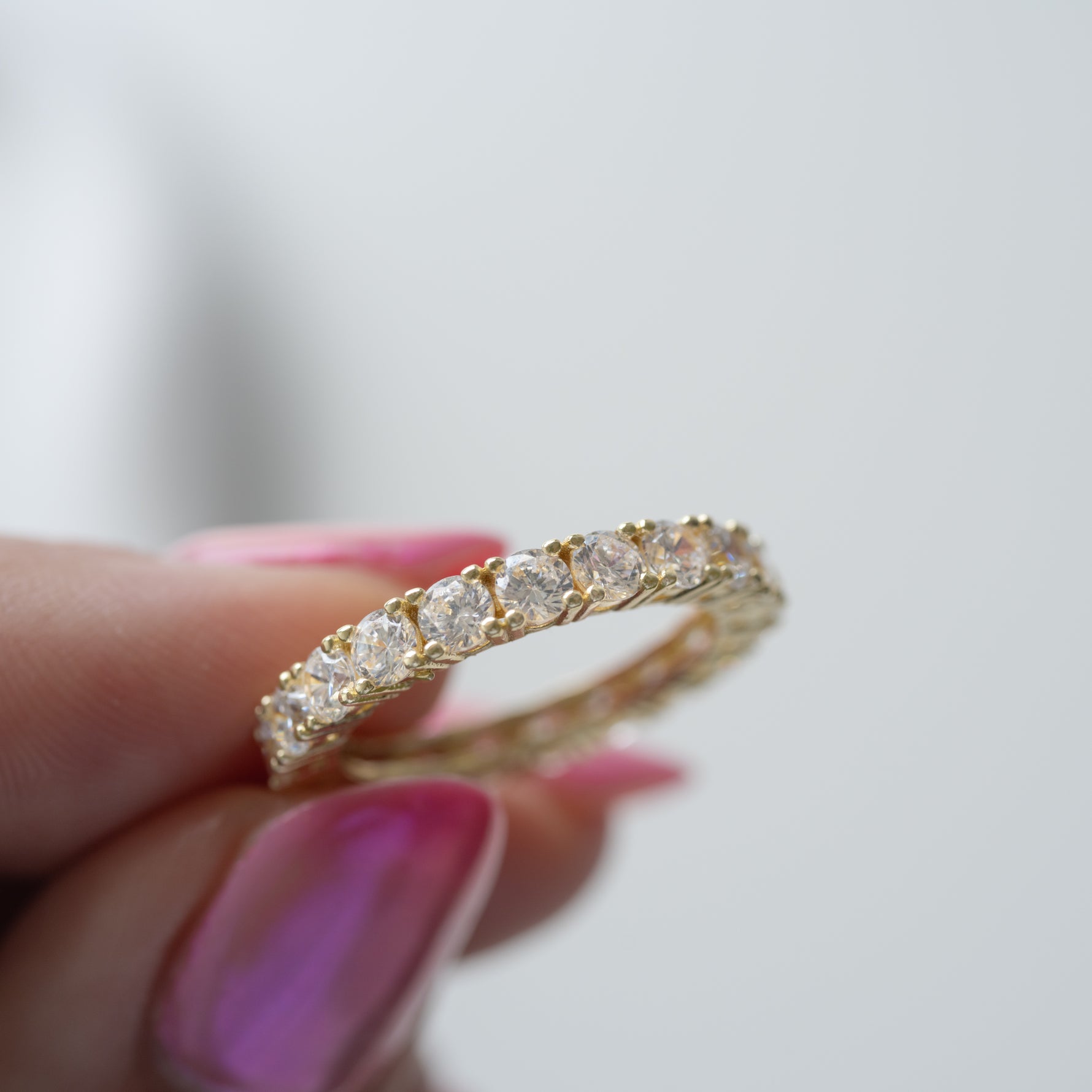 Model holding statement 3MM studded gold diamond eternity ring. 
