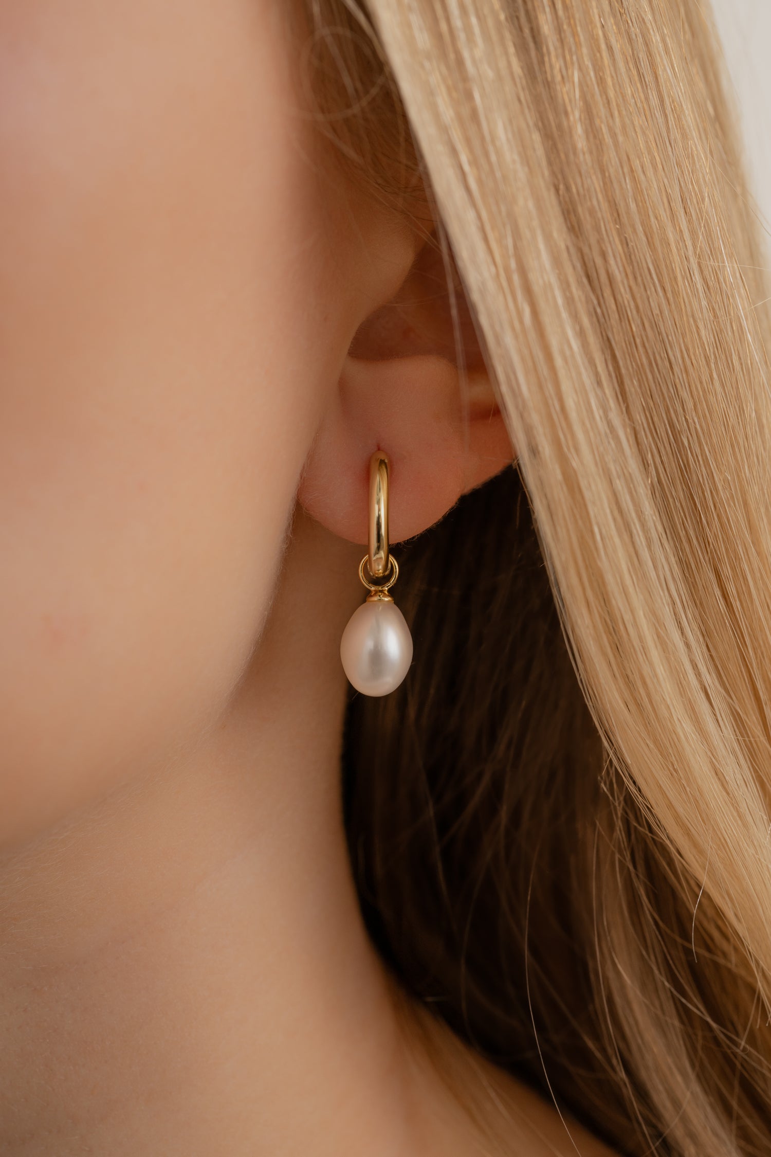 Model wearing gold minimalist huggie hoops with elegant pearl charms