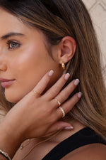 Model wearing sleek gold tube hoop earrings with minimalist design