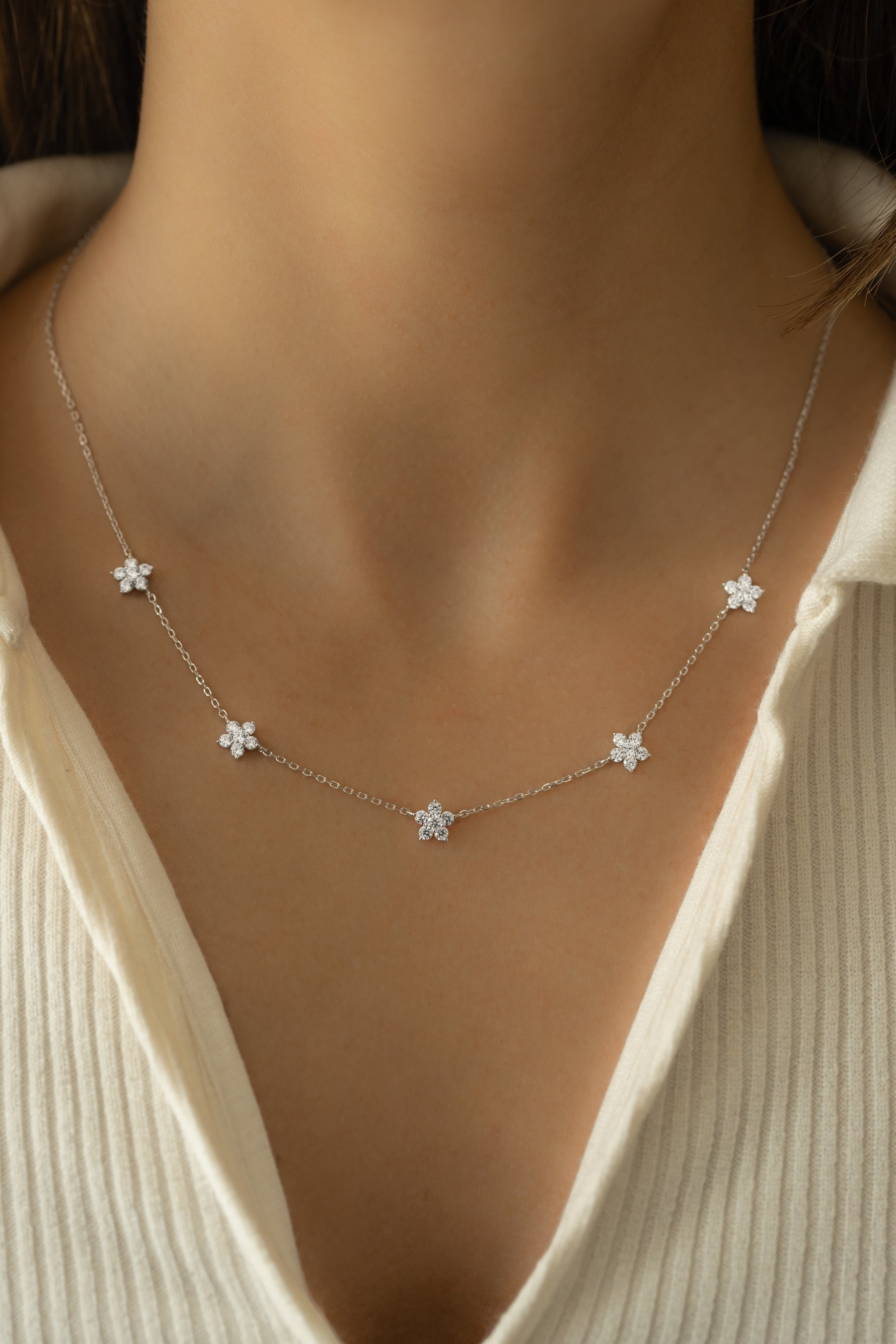 Model wearing delicate silver flower cz charm necklace. 