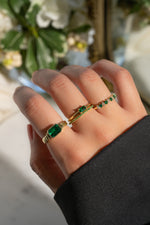 Model wearing emerald birthstone rings in a stack. 