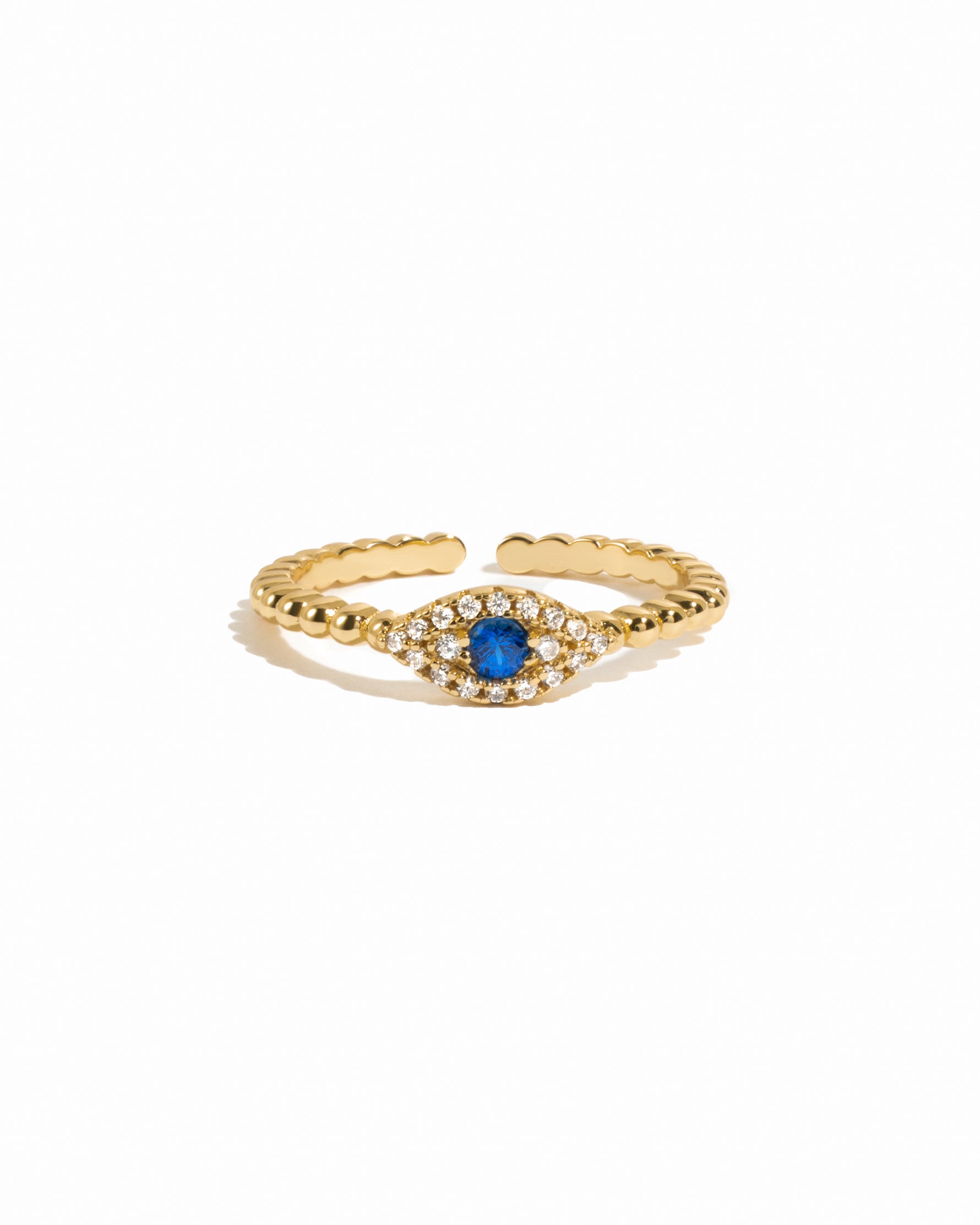 Dainty gold beaded adjustable evil eye ring with sapphire center on white background. 