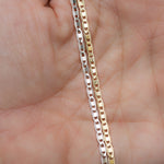 Model holding gold and silver delicate plain chain ankle bracelets