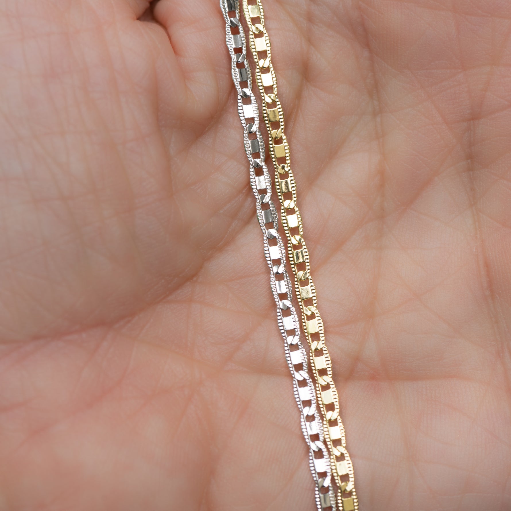 Model holding gold and silver delicate plain chain ankle bracelets