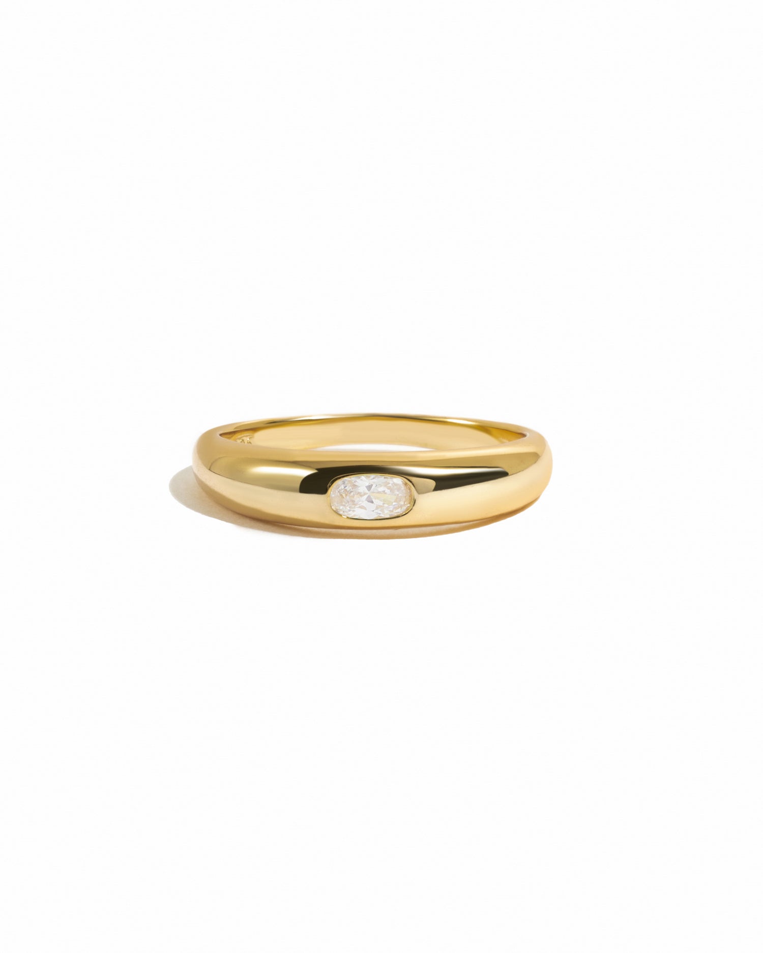 Gold oval cz bezeled dome ring on white background.
