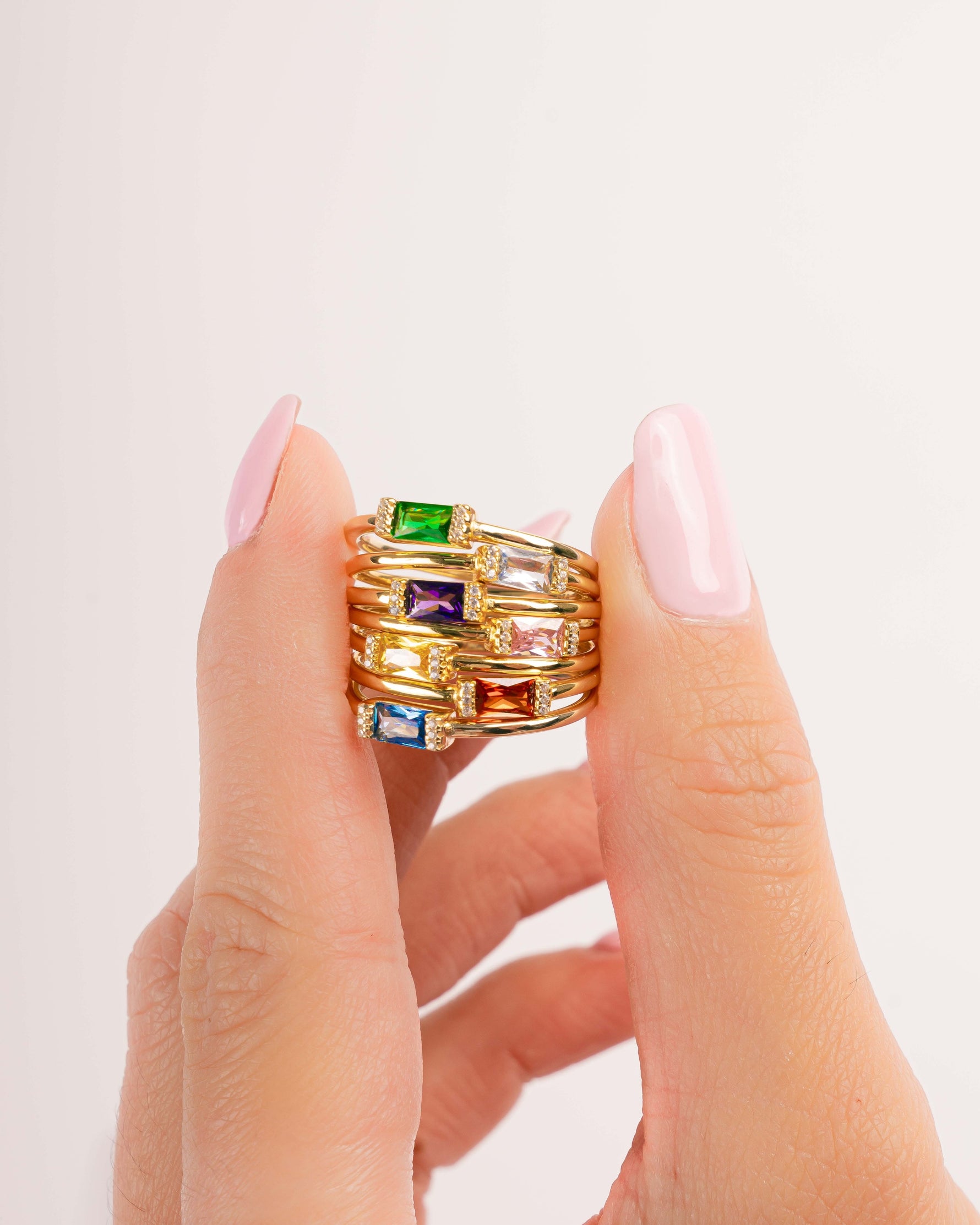 Gold rings with birthstone rings in between fingers