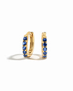 Gemstone earrings gold sapphire birthstone cz huggies on white background.