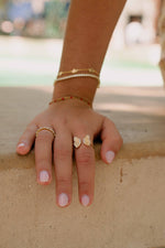 Model wearing summery gold rings and bracelets including a statement adjustable gold butterfly ring and a gold diamond eternity band. 