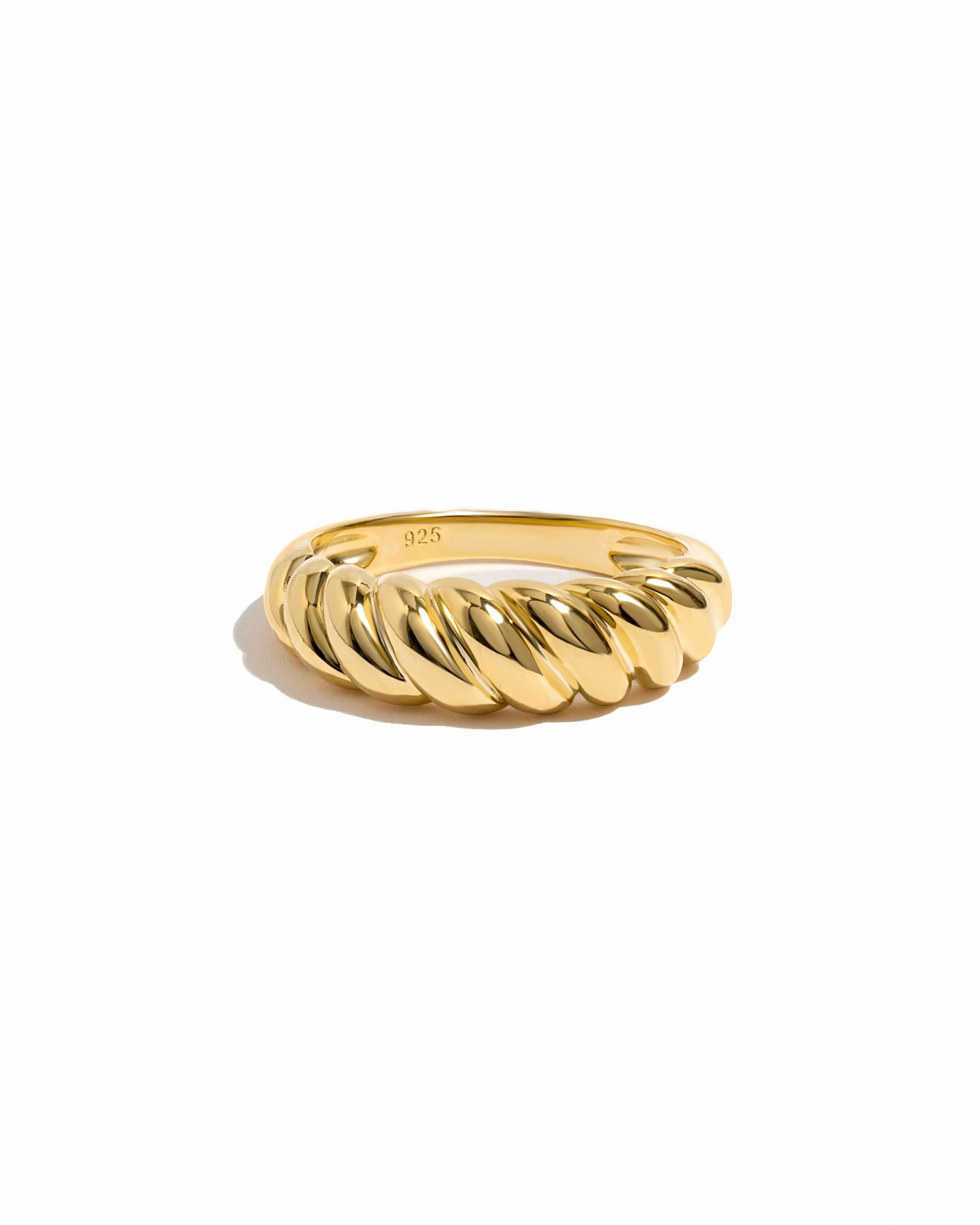 Gold croissant ring on white background.
