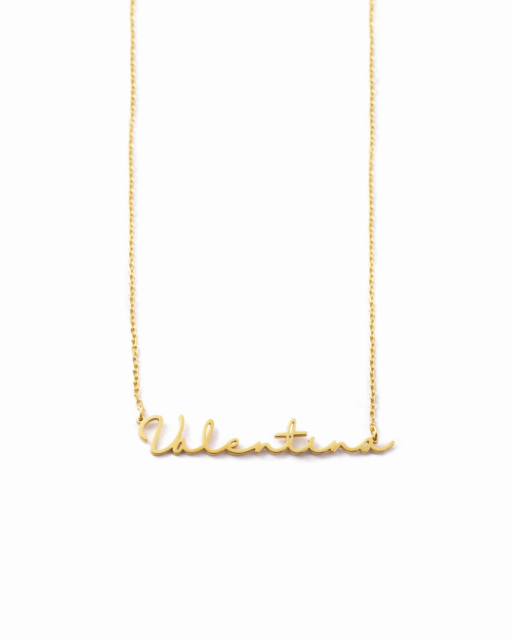 Gold custom script name necklace with a dainty chain on white background