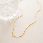 Delicate gold chain necklace in soft lighting.