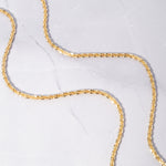 Sparkly gold diamond cut chain necklace on marble background.