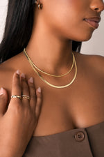 Model wearing gold diamond cut necklace with herringbone chain necklace. 