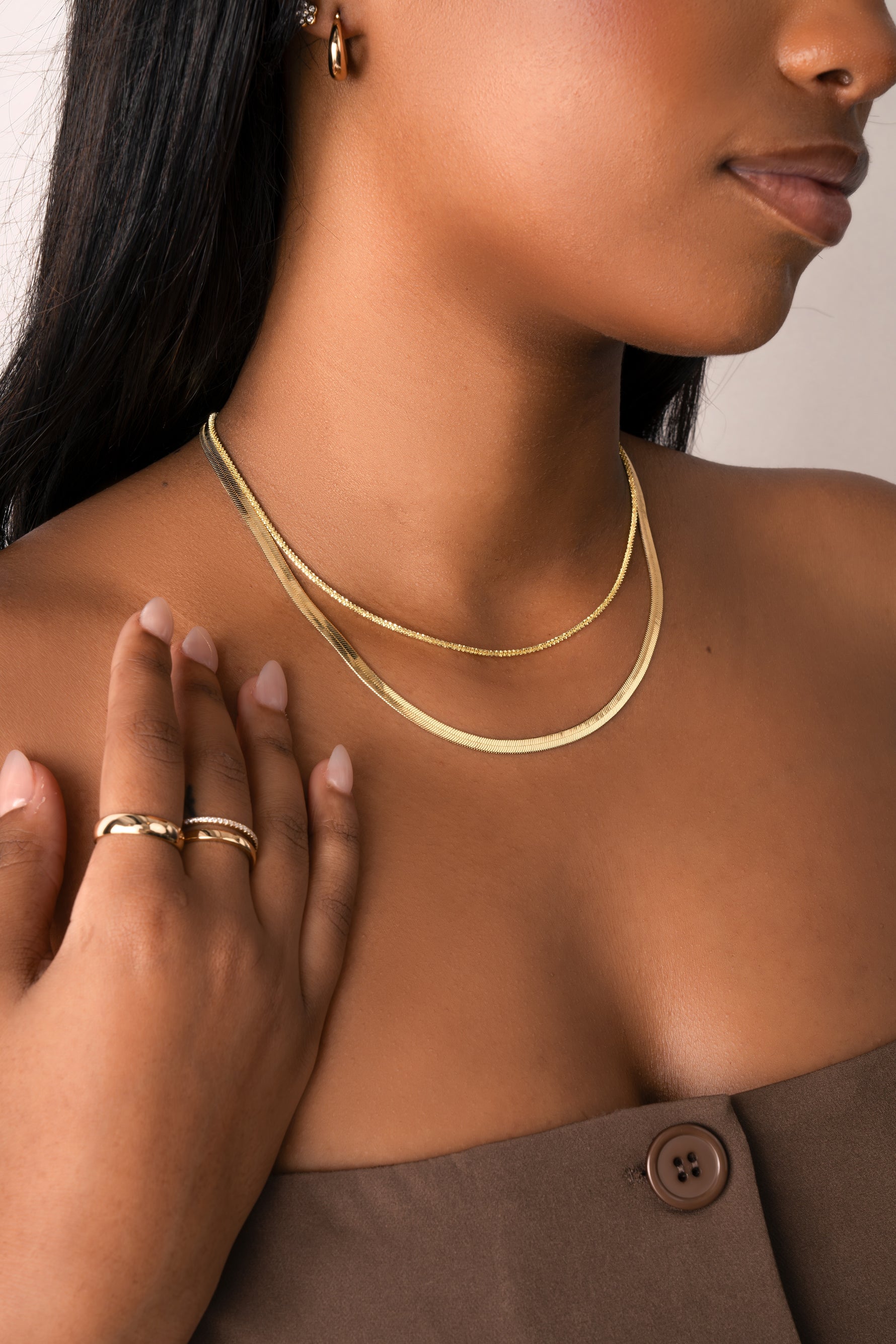 Model wearing gold diamond cut necklace with herringbone chain necklace. 