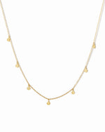Dainty gold disc charm necklace on white background.