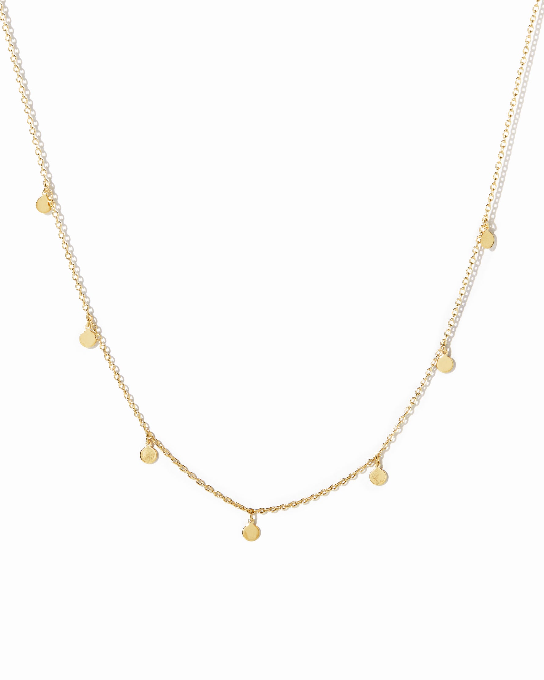 Dainty gold disc charm necklace on white background.