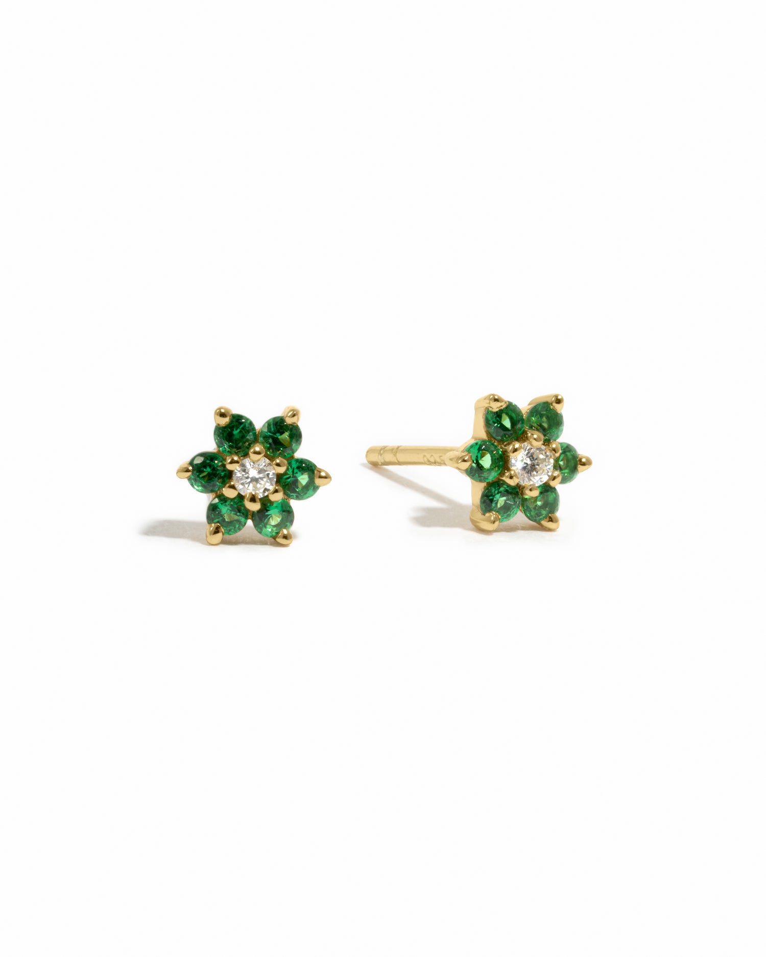 Dainty gold emerald birthstone flower stud earrings with white diamond in the center on white background.
