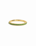 Gold dainty emerald eternity ring on white background. 
