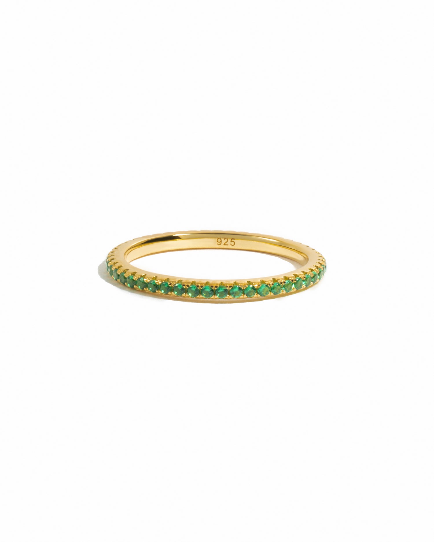 Gold dainty emerald eternity ring on white background. 