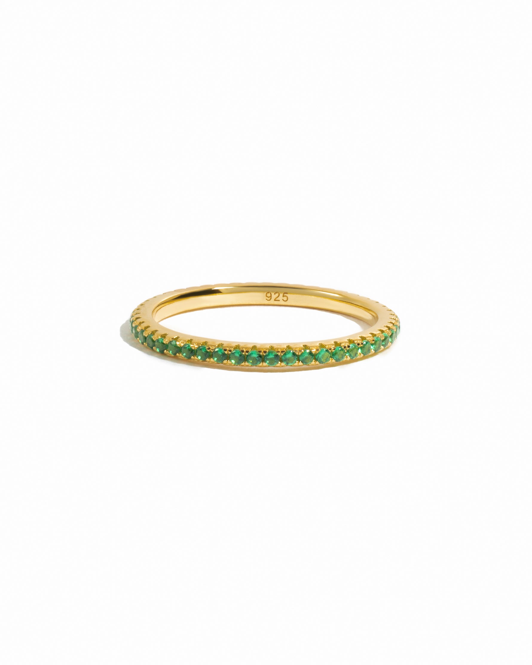 Gold dainty emerald eternity ring on white background. 