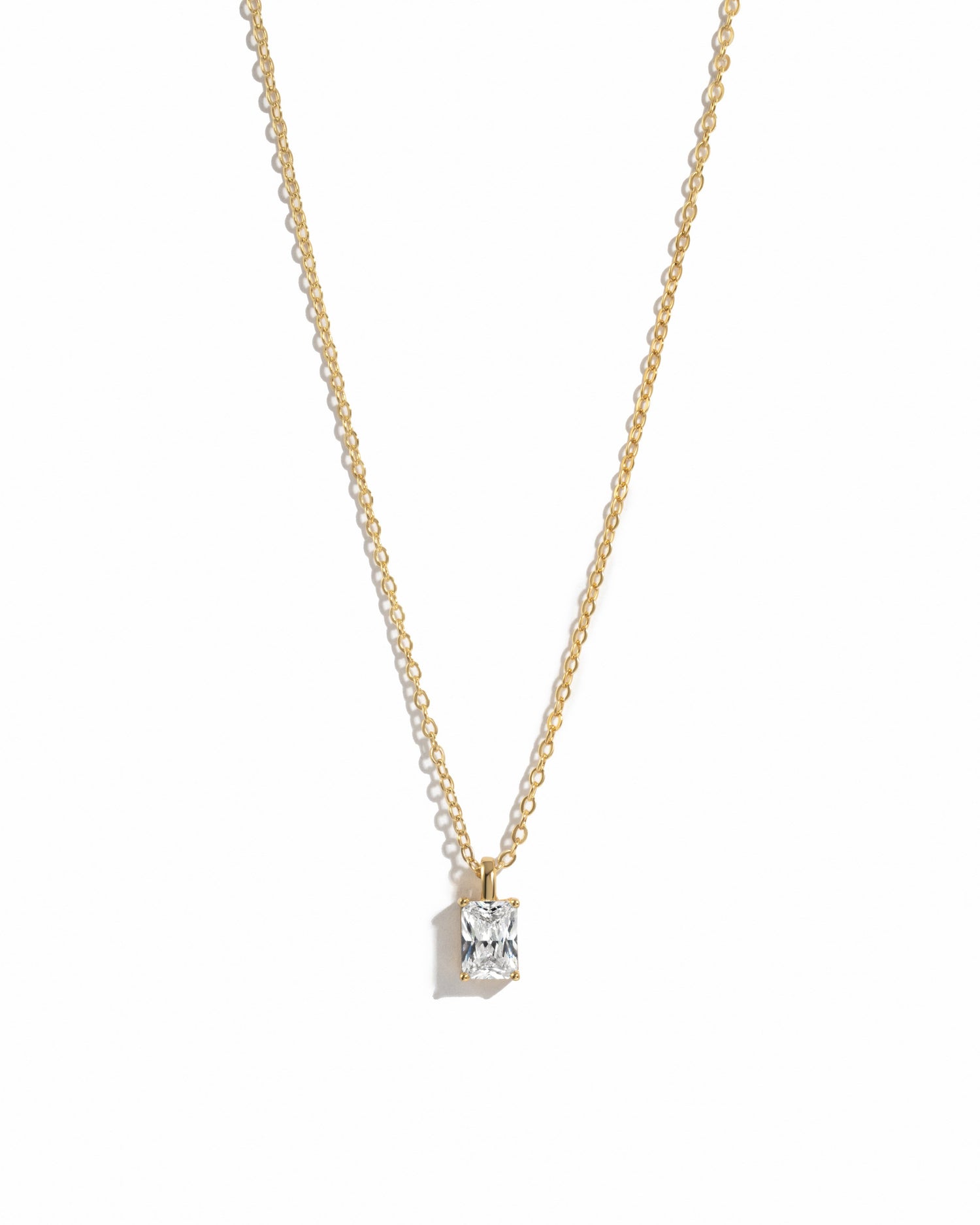 gold diamond emerald cut necklace on white background