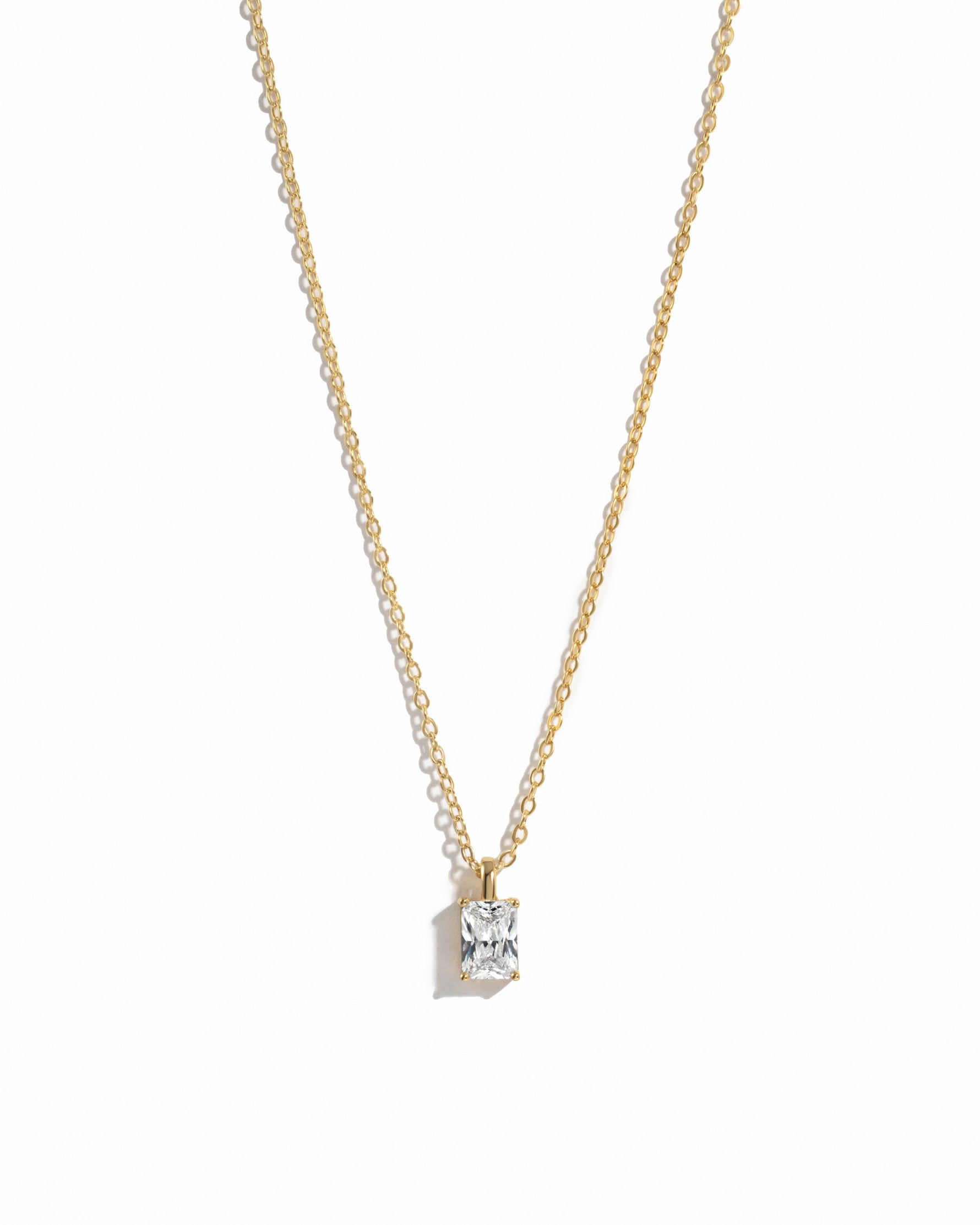 gold diamond emerald cut necklace on white background