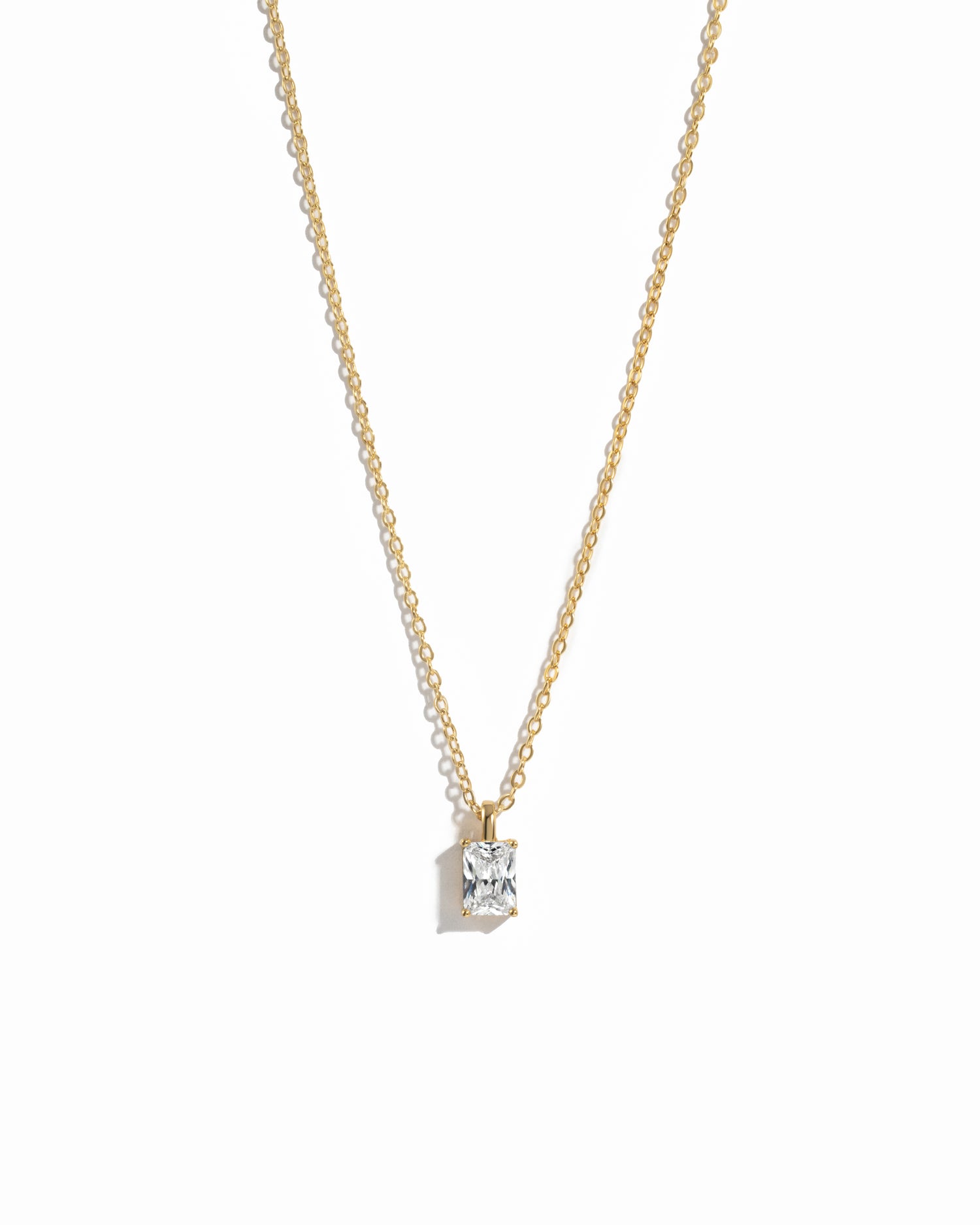 gold diamond emerald cut necklace on white background