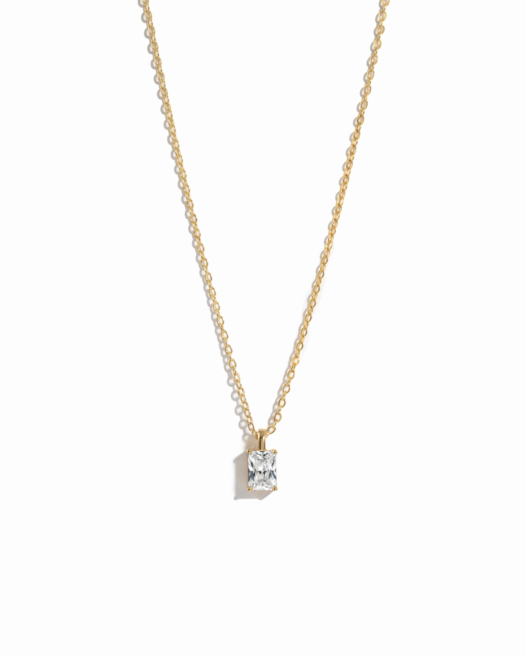 gold diamond emerald cut necklace on white background