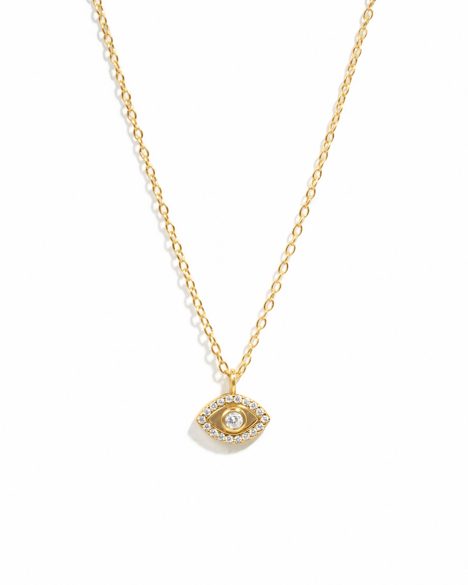 Minimalist gold evil eye pendant necklace on white background.