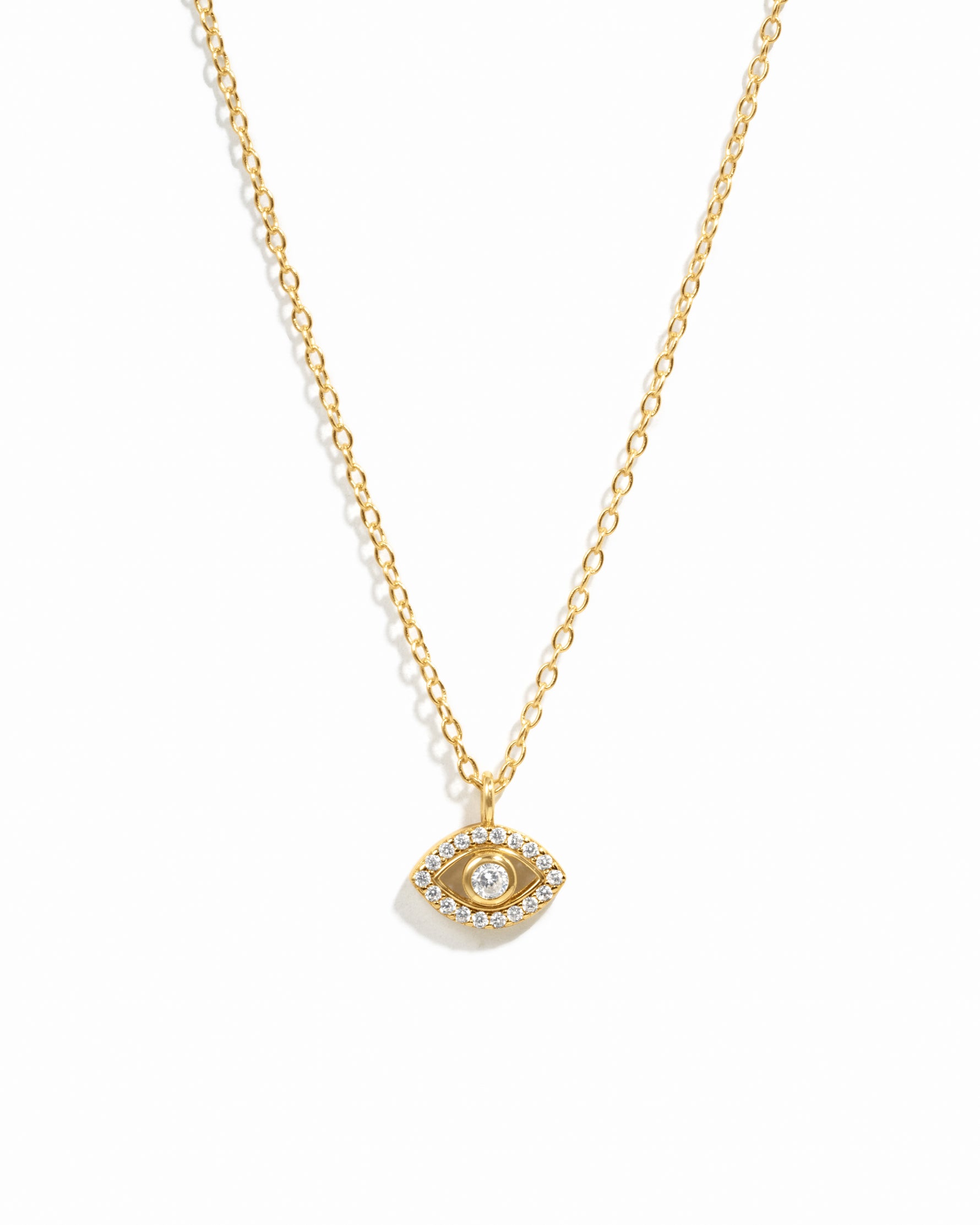 Minimalist gold evil eye pendant necklace on white background.