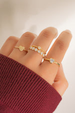 Model wearing delicate gold rings with a heart feminine theme. 
