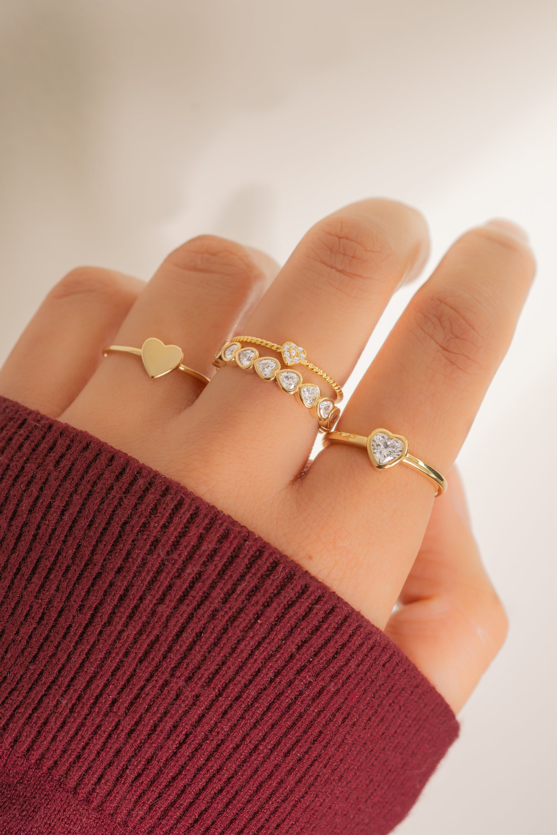 Model wearing delicate gold rings with a heart feminine theme. 